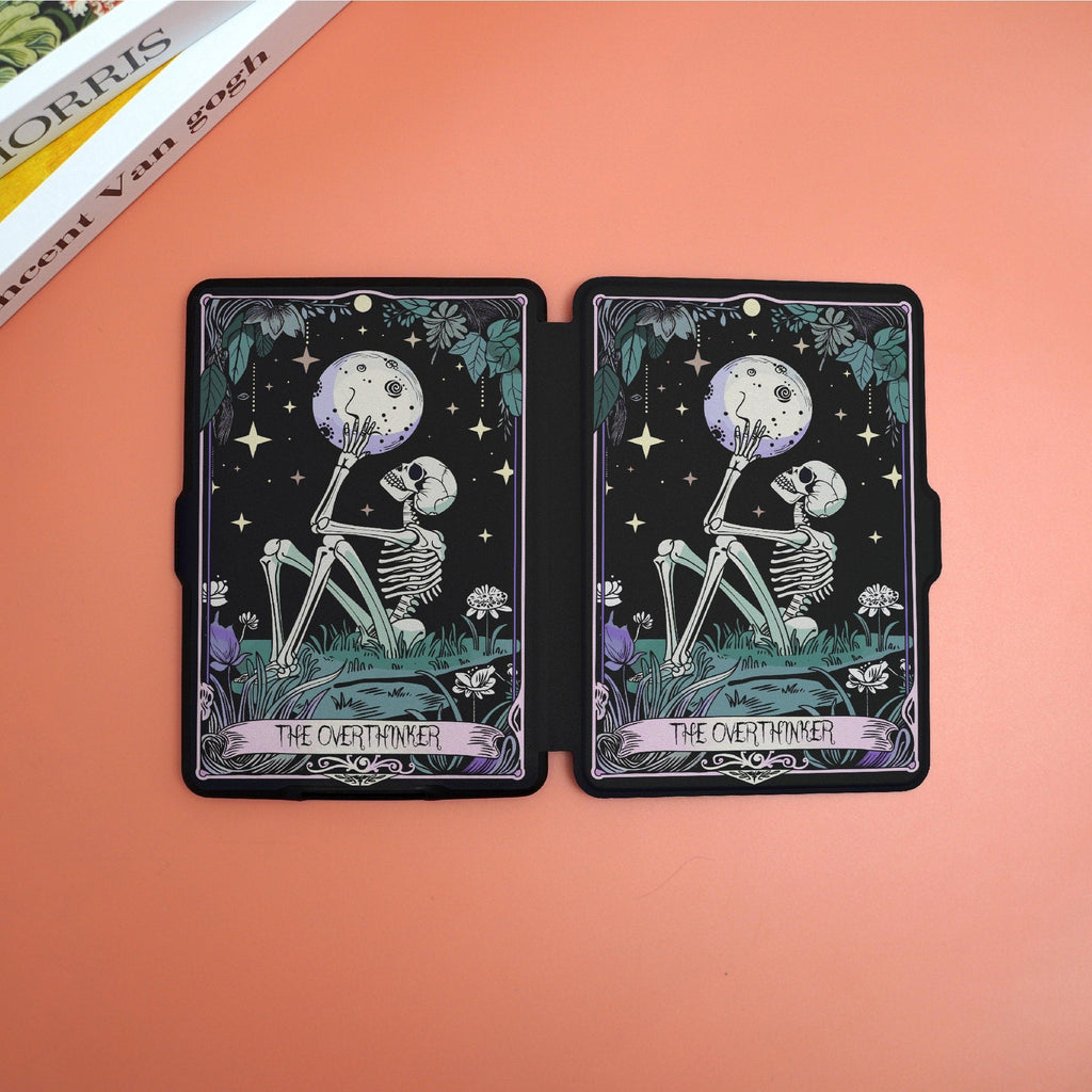 Two tarot cards titled 'The Overthemer' on a peach-colored surface with a book partially visible.